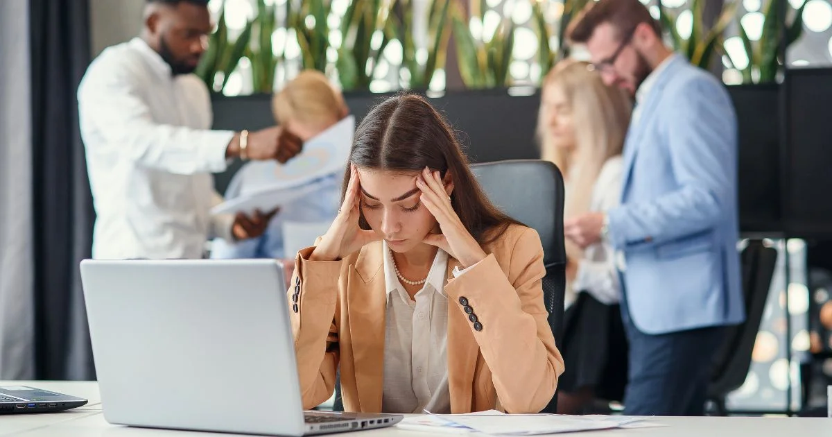 Stressed businesswoman holding head while working on laptop.